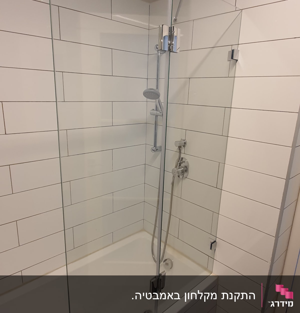 מקלחת עם דלת זכוכית וברז מתכת על קיר אריחים לבנים